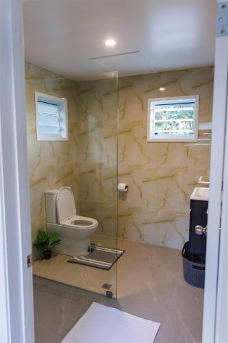 a bathroom with a toilet and a glass wall at Muri Ocean View Villas in Ngatangiia