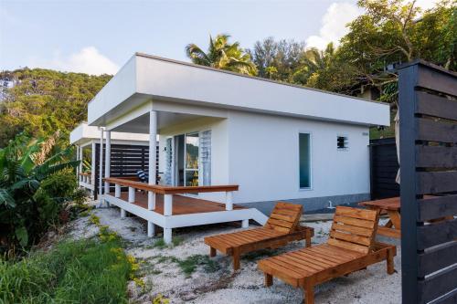 a small white house with two wooden chairs at Muri Ocean View Villas in Ngatangiia
