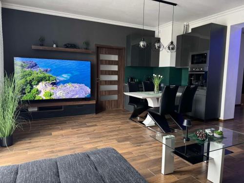 a living room with a large television and a dining table at NewPlace Luxury Apartment in Sátoraljaújhely