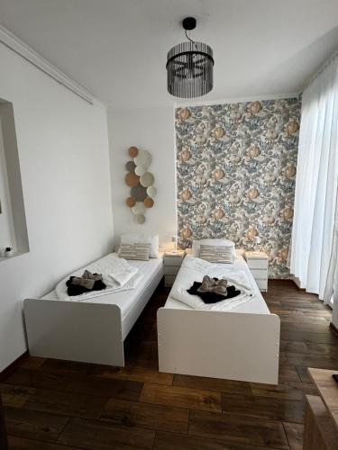 two beds in a white room with a wall at NewPlace Luxury Apartment in Sátoraljaújhely