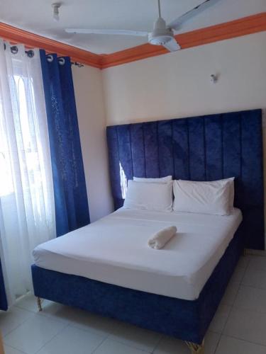 a large bed with a blue headboard in a room at Summer luxury apartments in Mombasa