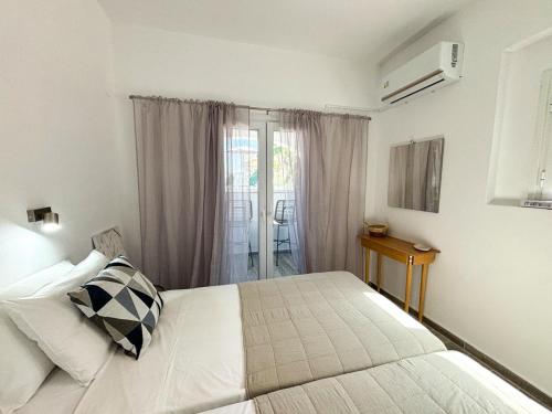 a white bedroom with a bed and a window at Kalami Bay Apartment in Kalami