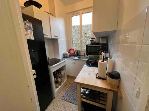 a small kitchen with a black refrigerator and a counter at Sublime appartement cosy près de la Tour Eiffel in Paris