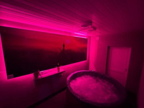 baño rosa con bañera y TV en Hornby Hottub and Jacuzzi Suites, en Blackpool