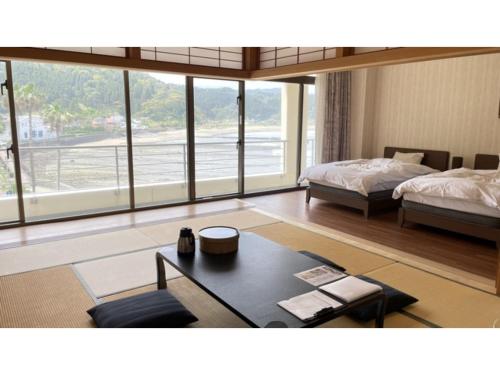 a bedroom with two beds and a table and a room with windows at Hotel Aoshima Cinqmale - Vacation STAY 67416v in Miyazaki