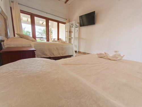 a bedroom with two beds and a tv on the wall at Costa Beach in Zorritos