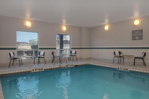 a swimming pool with chairs and a table and chairs at Spark by Hilton El Paso University in El Paso