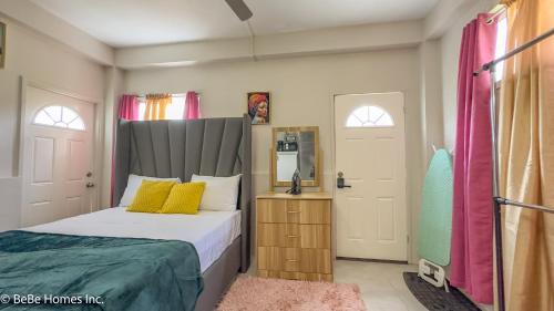 a bedroom with a bed with yellow and green pillows at Aquoia Luxe Suite - 12min from UVF Airport in Vieux Fort