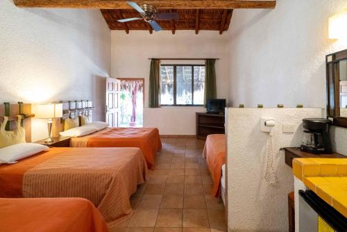 a hotel room with three beds and a window at Hotel Palmas De Cortez in Los Barriles