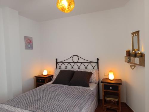 a bedroom with a bed with two night stands and two lights at Casa Walt in Mojácar