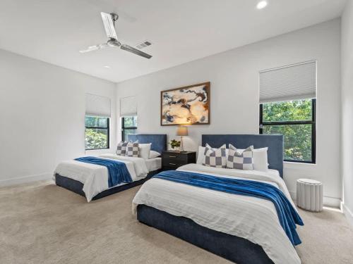 two beds in a bedroom with white walls and windows at Stylish Retreat Great Location Patio Parking in Dallas
