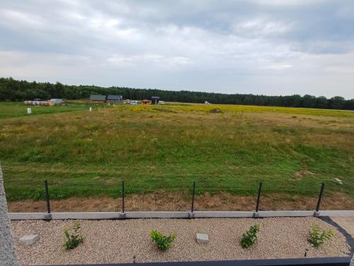 a field of grass with a farm in the background at Przystań Łukęcin in Łukęcin