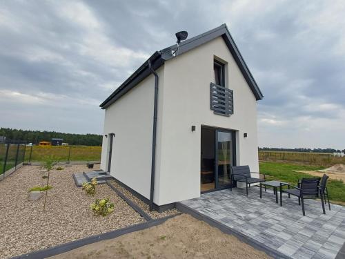 a small white building with two chairs and a table at Przystań Łukęcin in Łukęcin