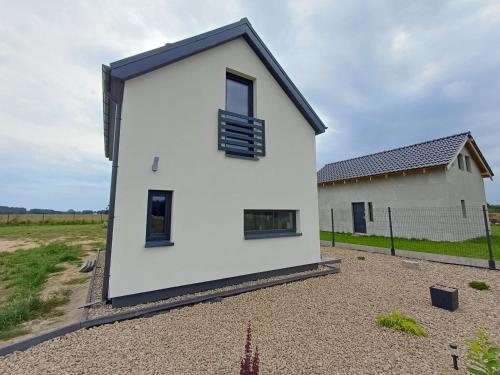 a white house with black windows on a gravel yard at Przystań Łukęcin in Łukęcin