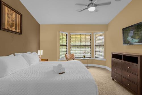 a bedroom with a white bed and a dresser at 4BR Disney Family Townhouse Resort in Orlando - with Resort Pool, Gym, Games, & Jacuzzi in Orlando