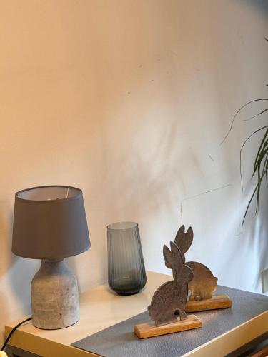two wooden rabbits sitting on a table next to a lamp at A casa di Tina in Genzano di Roma