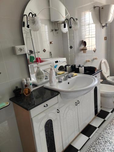a bathroom with a sink and a mirror and a toilet at Holiday Calabria Rooms in Lamezia Terme