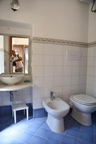 a person taking a picture of a bathroom with a toilet and sink at MEITHRAS holiday homes in Agrigento