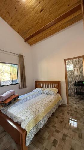 a bedroom with a large bed with a wooden ceiling at Recanto da Paz - Monte Verde in Monte Verde