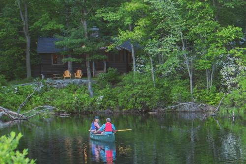 two people in a boat on a lake with a cabin at Harriman Outdoor Center in Haverstraw
