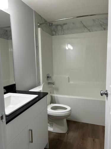 a white bathroom with a toilet and a sink at Kris Comfort Garden Suite in Edmonton