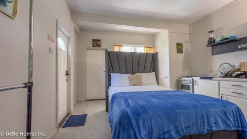 a small bedroom with a bed with a blue blanket at Galexi Aura Suite - 12min from UVF Airport in Vieux Fort