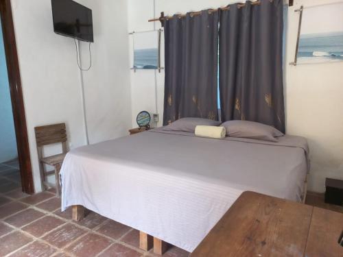 a bedroom with a bed and a television and a table at Hotel Quinto Sol in Mazunte