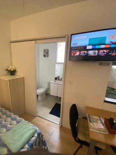 a room with a television on a wall with a bedroom at Studio près de Paris Aeroport CDG 2 minutes de la gare in Arnouville-lès-Gonesse