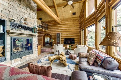 a living room with a stone fireplace in a log cabin at Secluded Angel Fire Retreat Deck and Stunning View! in Angel Fire