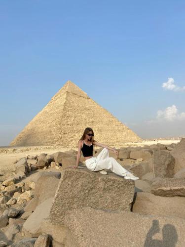a woman sitting on the rocks in front of the pyramids at Master Kings of the pyramids and Sphinx in Giza