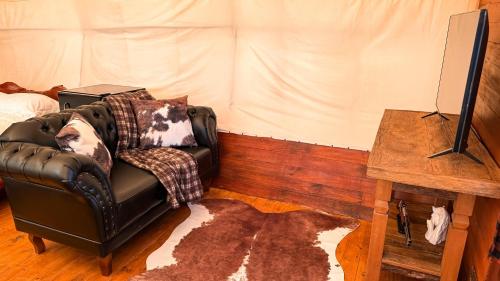 a living room with a leather chair and a table at Wagon Cella faroeste com Spa em Campos in Campos do Jordão