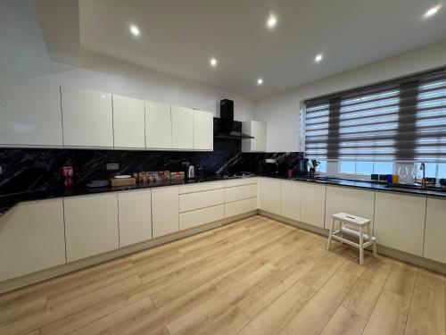 a kitchen with white cabinets and a wooden floor at The Bishop Retreat in London