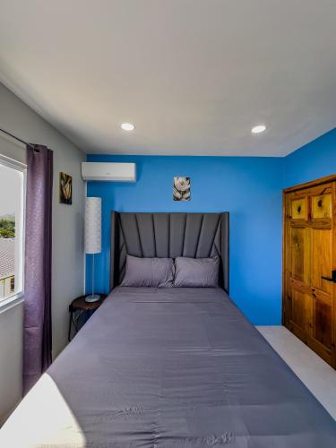 a bedroom with a blue wall and a bed at Khepri Soleil Suite - 12min from UVF Airport in Vieux Fort