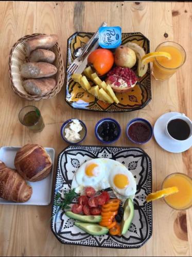 a table topped with plates of breakfast food with eggs and bread at Surfer's Heimat Hostel in Tamraght Ouzdar
