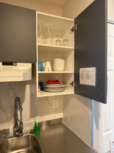 a kitchen with a sink and a shelf with dishes at Sand Pebbles Inn in Qualicum Beach