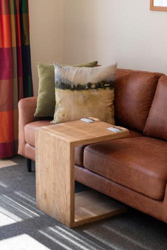 a brown couch with a wooden coffee table at Tussock Peak Lodge in Hanmer Springs