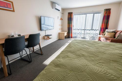 a hotel room with a television and a desk and chairs at Tussock Peak Lodge in Hanmer Springs