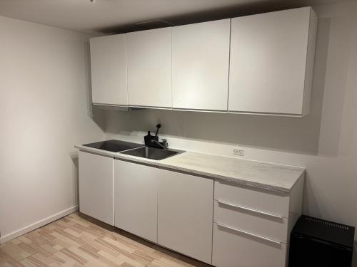 a kitchen with white cabinets and a sink at Nordnest, 6 min from Airport in Copenhagen