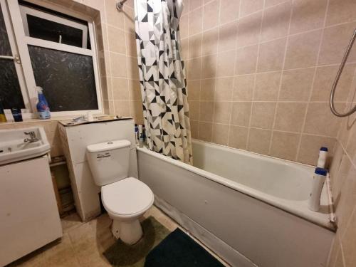 a bathroom with a toilet and a tub and a sink at Budget Room Stevenage Town Centre in Stevenage