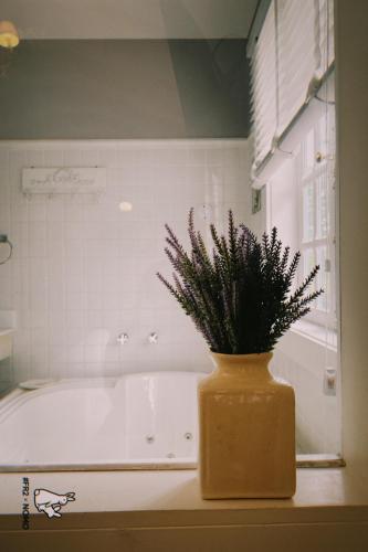 a yellow vase with a plant in front of a bath tub at La Belle Provence in Itaipava