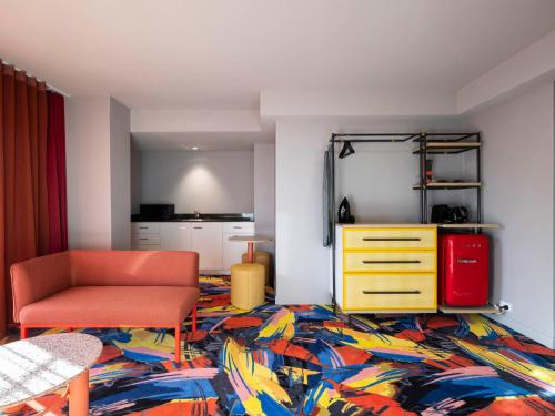 a living room with a chair and a colorful rug at Adge Hotel and Residences in Sydney