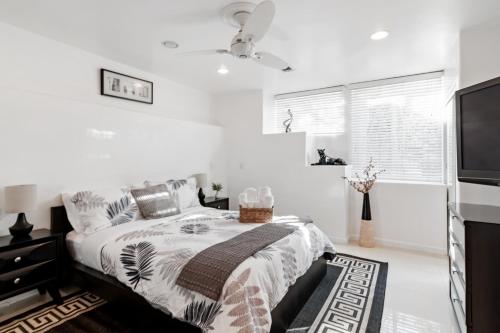 a white bedroom with a bed and a flat screen tv at Quiet Home with Spectacular Scenic Mountain Views near Universal Studios Hollywood in Los Angeles