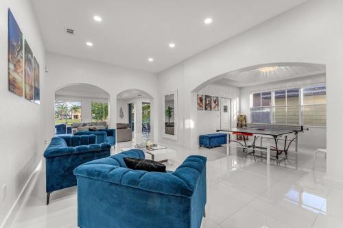 a living room with blue couches and a ping pong table at The Lake house 305 , Perfect Sunset in Tamiami