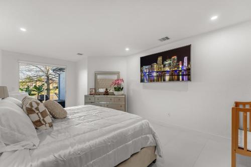 a white bedroom with a bed and a picture on the wall at The Lake house 305 , Perfect Sunset in Tamiami