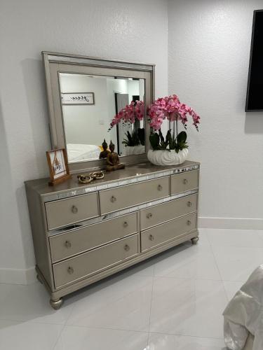 a dresser with a mirror and pink flowers on it at The Lake house 305 , Perfect Sunset in Tamiami