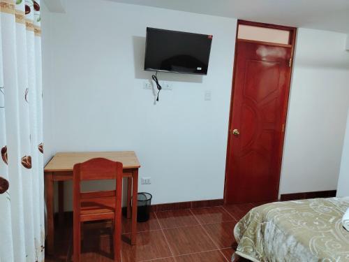 a bedroom with a table and a bed and a tv on a wall at PATAWASI Guest House Cusco in Cusco