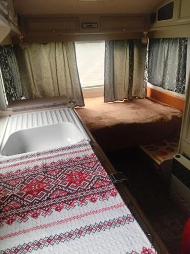 a camper van with a bed and a rug at Camping -Dor de Munte -Ceahlau in Bistricioara