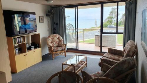 a living room with a couch and a tv and a balcony at 15 Beachpark Apartments in Port Macquarie