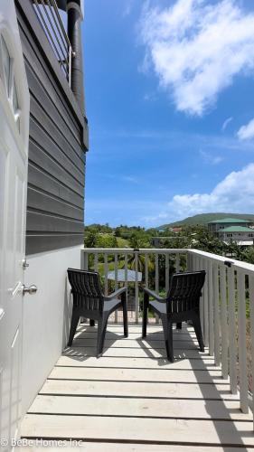 two benches sitting on a porch with a view of the ocean at Villa Opulence - 12min from UVF Airport in Vieux Fort