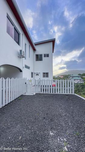 a white house with a fence in front of it at Villa Opulence - 12min from UVF Airport in Vieux Fort
